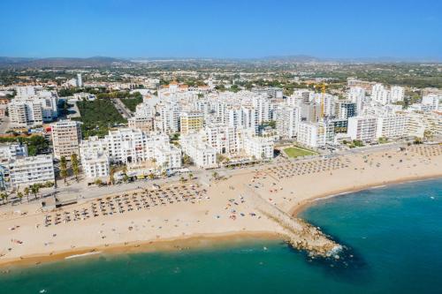 an aerial view of a beach with people and buildings at Hotel Atismar in Quarteira