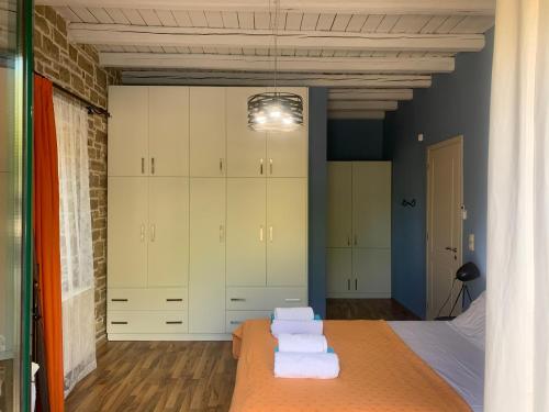 1 dormitorio con armarios blancos y toallas en una cama en Carob Villa en Moírai