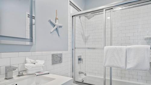 a white bathroom with a shower and a sink at The Hermitage at Napeague in Amagansett