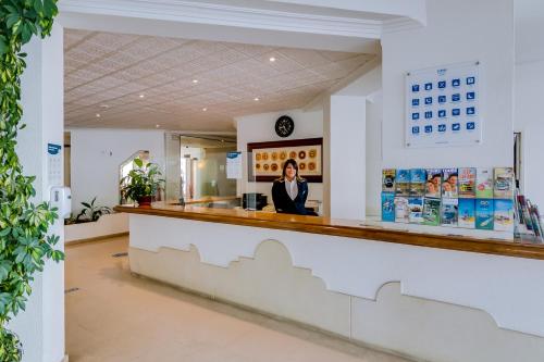 a woman standing at the counter of a pharmacy at Hotel Atismar in Quarteira