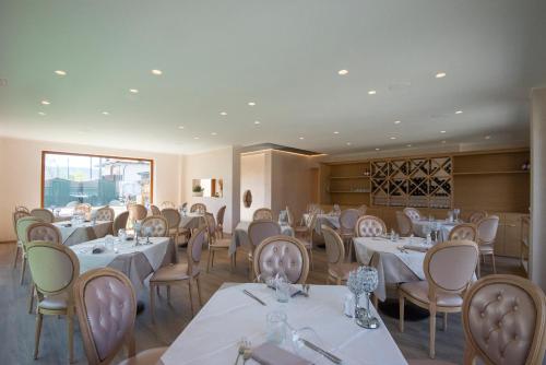 jadalnia z białymi stołami i krzesłami w obiekcie Villa Ciardi Wellness Hotel & Ristorante w mieście Roana