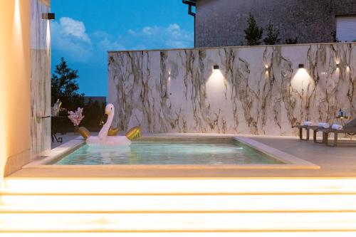a swimming pool with a swan in the water at Villa Nina - Apartments with pool near the sea in Rabac