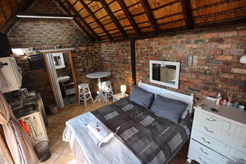 a bedroom with a bed and a brick wall at Riverstay in Kroonstad