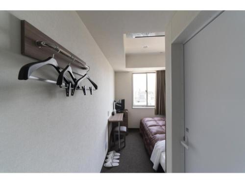 a hotel room with a bed and a desk with shoes at R&B Hotel Hakata Ekimae 2 - Vacation STAY 40725v in Fukuoka