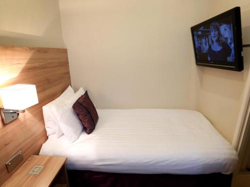a small room with a bed and a television at The Chocolate Box Guest House in Bournemouth