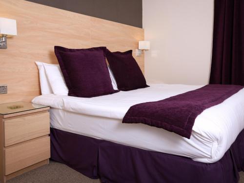 a bedroom with a large bed with purple pillows at The Chocolate Box Guest House in Bournemouth