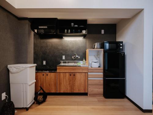 a kitchen with a black refrigerator and wooden cabinets at REQRAS Sakuramachi - Vacation STAY 52733v in Kumamoto