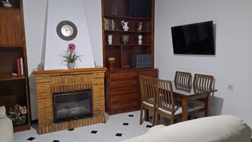 sala de estar con chimenea, mesa y sillas en Casa El Villa, en Zahara de la Sierra