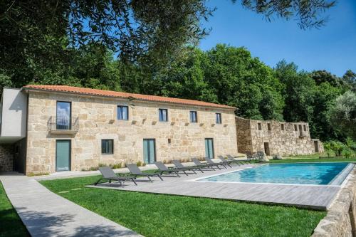 an old stone building with a swimming pool and chairs at Quinta da Mourinha in Arcos de Valdevez