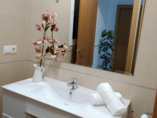 a bathroom sink with a vase with flowers on it at La Carbonera in Sanlúcar de Guadiana