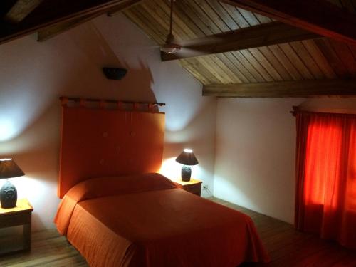 1 dormitorio con cama y cortina roja en La Residencia del Paseo, en Las Terrenas