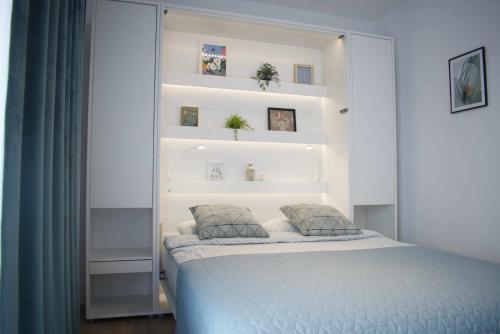 a bedroom with a bed with white walls and shelves at Apartament na Wydmach Międzywodzie in Międzywodzie