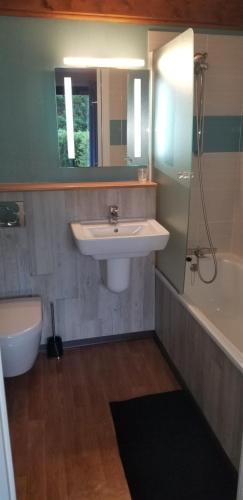 a bathroom with a sink and a tub and a toilet at Les Dineux Village in Trémeur