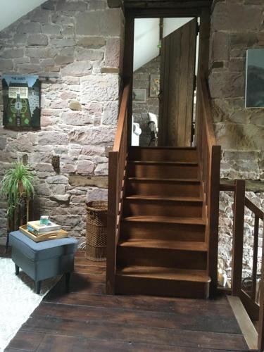 a staircase in a stone building with a stone wall at Historic converted byre in courtyard of 16C house in Caldbeck
