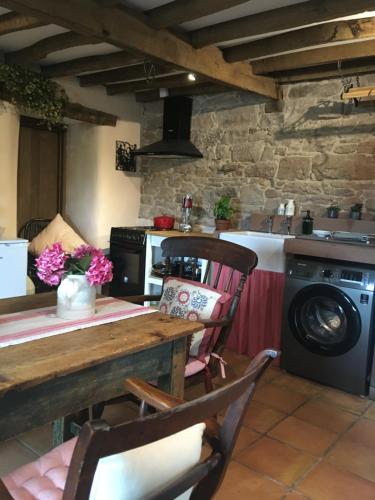 a kitchen with a table and a washing machine at Historic converted byre in courtyard of 16C house in Caldbeck
