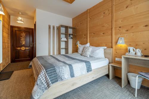a bedroom with a bed and a wooden wall at Stachelisko - domki i pokoje in Chochołów