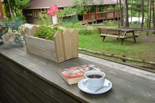 a cup of coffee sitting on a table with a book at Abant Korudam bungalov butik otel in Abant