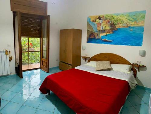 アジェーロラにあるCasale Paradisoの赤いベッドと壁に絵画が飾られたベッドルーム1室