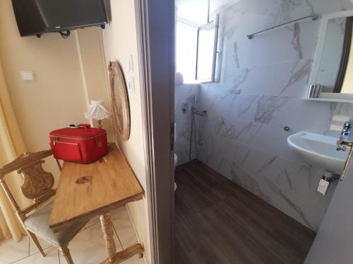 un baño con lavabo y una maleta roja en una mesa. en Anthemio, en Loutraki