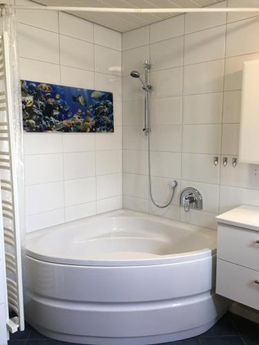 a white tub in a bathroom with a painting on the wall at Ferienwohnung Panoramablick Ennepetal in Ennepetal