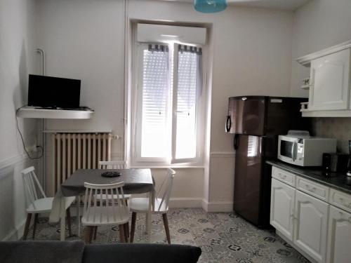 une petite cuisine avec une table et un four micro-ondes dans l'établissement Doux Ombrages, à La Bourboule