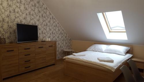a bedroom with a bed and a television on a dresser at Apartament z pięknymi widokami, około 900m do przejrzystego jeziora Choczewskiego, blisko morza in Perlino