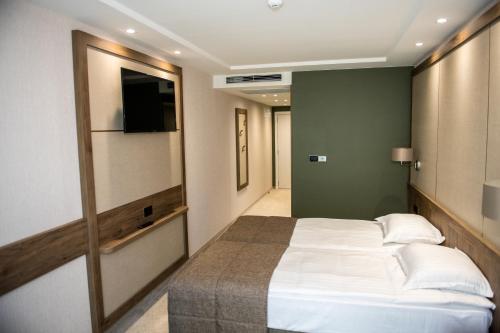 a bedroom with a large white bed and a green wall at Arletti Hotel in Ruse