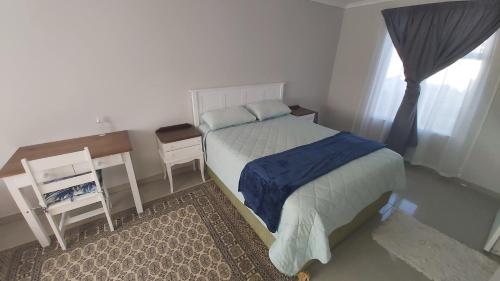 a bedroom with a bed and a desk and a window at Cottage self catering unit with ensuite. in East London