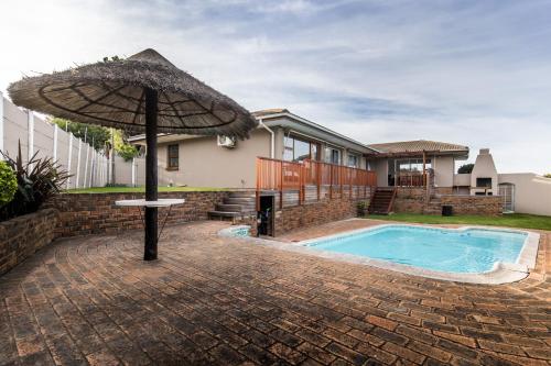 an umbrella in front of a house with a swimming pool at Cornerstone Guesthouse in Cape Town