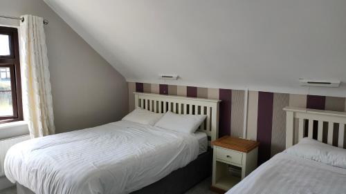 a bedroom with two beds and a window at Lios Éinne House Accommodation in Inisheer