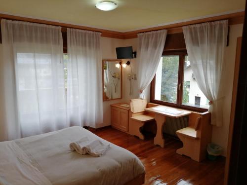 1 dormitorio con cama, escritorio y ventana en Hotel Edelweiss, en Val di Zoldo