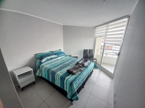 - une chambre avec un lit doté d'une couverture bleue et d'une fenêtre dans l'établissement vista playa los molles, à Los Molles