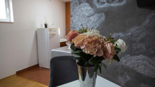 een vaas gevuld met bloemen zittend op een tafel bij Prva Apartment in Novi Pazar