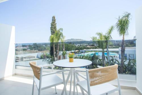 a table and chairs in a balcony with a view of a pool at Vanik Suites in Faliraki