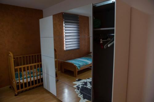 a room with a crib and a closet with a mirror at Prva Apartment in Novi Pazar