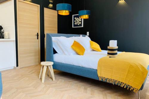 - une chambre dotée d'un lit bleu avec des oreillers jaunes et un tabouret dans l'établissement Suite Le CEZANNE, à Aix-en-Provence