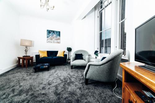 een woonkamer met 2 stoelen en een televisie bij Princes Street Apartment in Perth