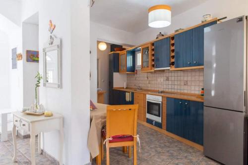 cocina con armarios azules, mesa y nevera en Almyra seaside house, en Kamarai
