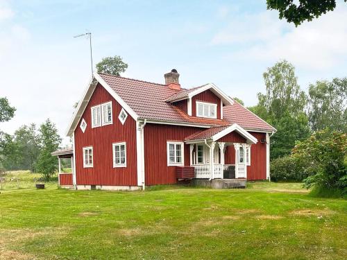 una casa roja con un patio verde en 8 person holiday home in VIRESTAD, en Virestad