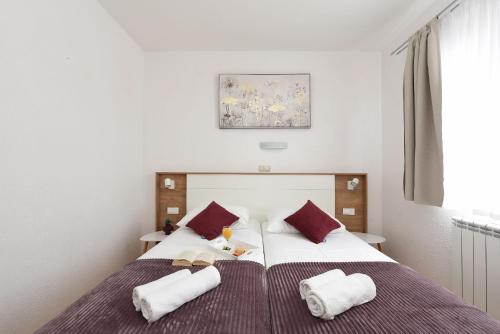 1 dormitorio con 2 camas y almohadas rojas y blancas en Apartments Amari, en Starigrad-Paklenica
