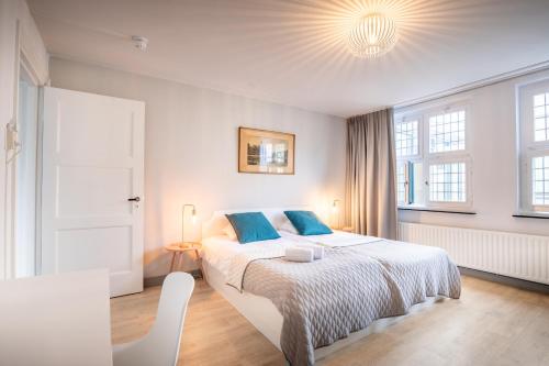 a bedroom with a large white bed with blue pillows at Hotel Nieuw Antiek in Helden