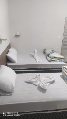 two beds with white sheets and towels on them at Pousada Quarto completo ar,wi fi e garagem gratuita in Aparecida