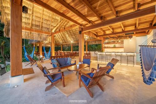 a patio with chairs and tables and a hammock at Hotel Gringo Perdido in El Remate