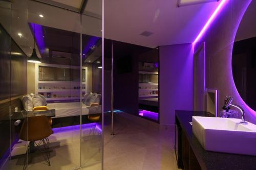 a bathroom with a sink and purple lighting at Oasis Motel in Piracicaba