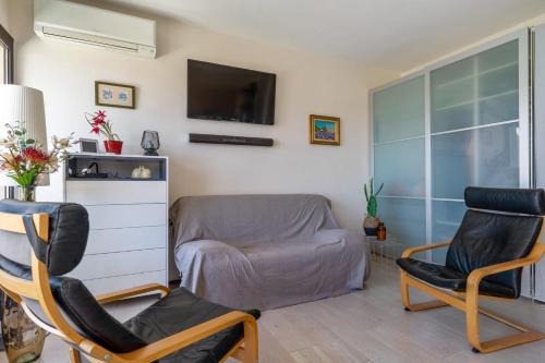 uma sala de estar com duas cadeiras e uma televisão em Superb bright flat with balcony and sea view in Cassis - Welkeys em Cassis