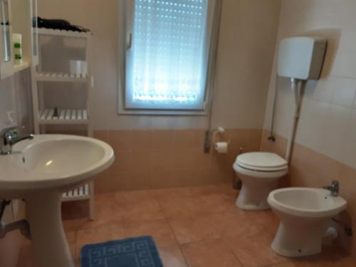 a bathroom with two sinks and a toilet and a window at Locazione Menini - Camere zona stazione in Padova