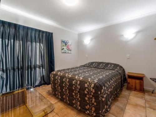 a bedroom with a bed and a large window at Cottage Park Thermal Motel in Tauranga