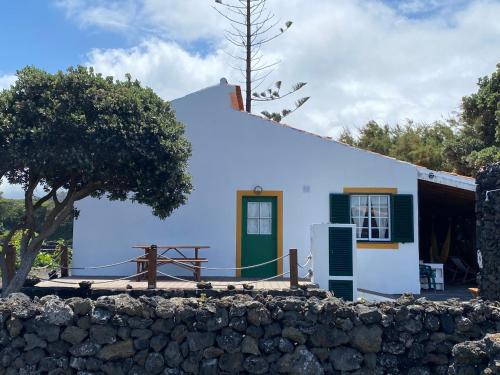 a white house with a green door and a fence at Casa da Costa in Madalena