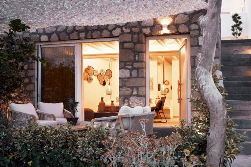 a patio with white chairs and a stone wall at Nirome Luxury Suites in Adamas
