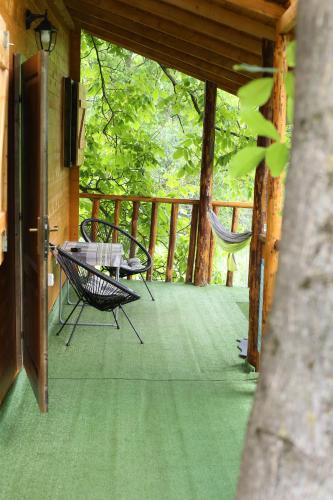 a porch with a hammock and a table and chairs at Casuta Veveritelor - Casuta in Copac in Moisei